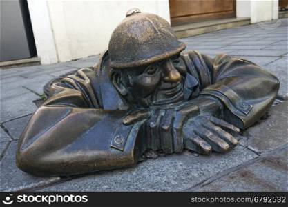 A bronze statue representing a street worker emerging from a manhole. On a street in the city centre of Bratislava, the capital city of Slovakia. Popular with tourists it is one of the most photographed statues in Bratislava.