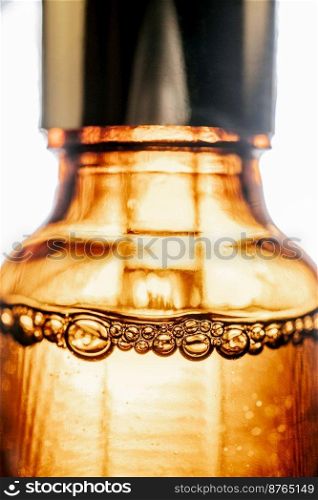 A brown cosmetic bottle with bubbles in the spotlight. Perfectly demonstrates the technological efficiency and effectiveness of cosmetics.. Pipette with cosmetic oil in a brown bottle with bubbles