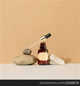 a brown glass bottle with a pipette and a brown label stands on a stone. Container for cosmetics