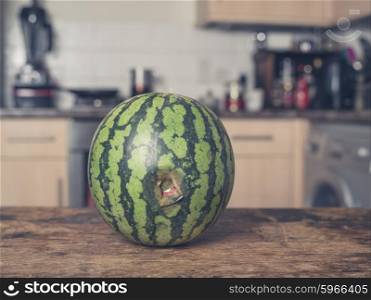 A bruised and rotten watermelon on a table in a kitchen