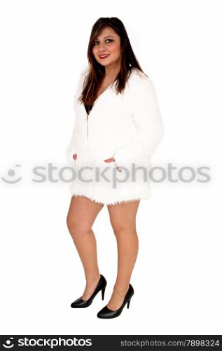 A brunette young woman standing isolated for white background wearinga short white jacket an high heels.