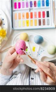 A brush in the process of painting Easter eggs with watercolors. Top view, vertical photo. A brush in the process of painting Easter eggs with watercolors. Top view, vertical photo.