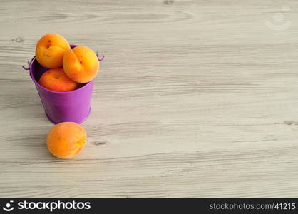 A bucket filled with apricots and one next to it.