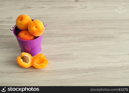 A bucket filled with apricots and one next to it.
