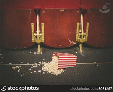 A bucket of spilled popcorn on the floor of a movie theater
