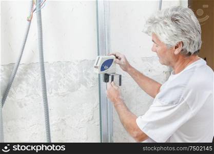 a builder measuring against wall