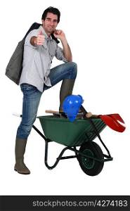 a builder posing near a wheelbarrow