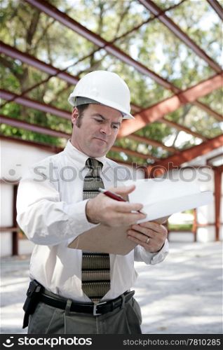A building inspector on site reviewing his notes. Vertical view.