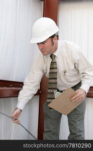 A building inspector testing the tension on a support wire in a steel frame bulding.