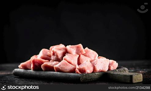 A bunch of chopped raw pork on a cutting board. On a black background. High quality photo. A bunch of chopped raw pork on a cutting board.