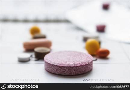 A bunch of different pills on a calendar background. Pills, supplements and medicines for the disease. Healthcare. A bunch of different pills on a calendar background. Pills, supplements and medicines for the disease.