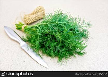 A bunch of dill, a skein of twine and a knife on the background of a granite table