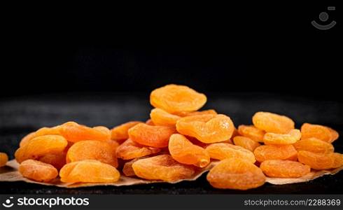 A bunch of dried apricots on the table. On a black background. High quality photo. A bunch of dried apricots on the table.