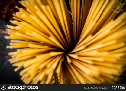 A bunch of dry pasta on the table. Against a dark background. High quality photo. A bunch of dry pasta on the table.