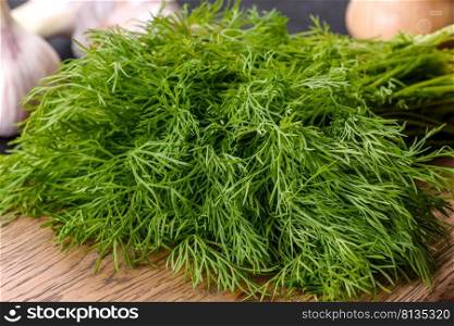 A bunch of fresh green dill on a wooden cutting board on a dark concrete background. Cooking at home. A bunch of fresh green dill on a wooden cutting board
