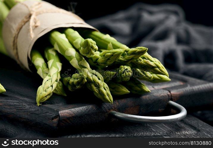 a bunch of fresh raw asparagus on a wooden black kitchen board, a healthy product