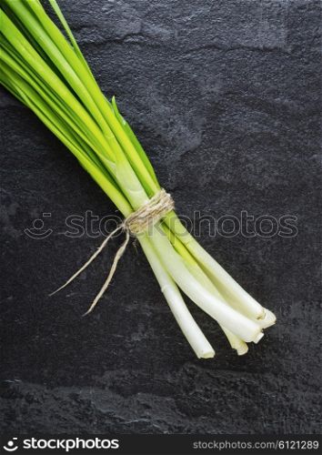 A bunch of green onions on a black stone table