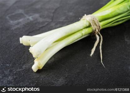 A bunch of green onions on a black stone table