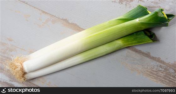 a bunch of leeks on a white wooden table