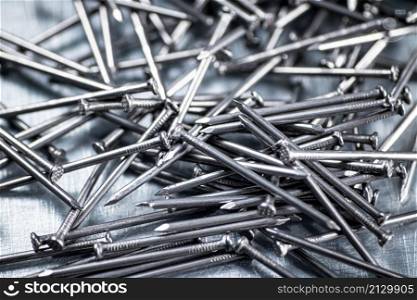 A bunch of nails on the table. On a gray background. High quality photo. A bunch of nails on the table.