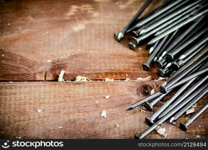 A bunch of nails on the table. On a wooden background. High quality photo. A bunch of nails on the table.