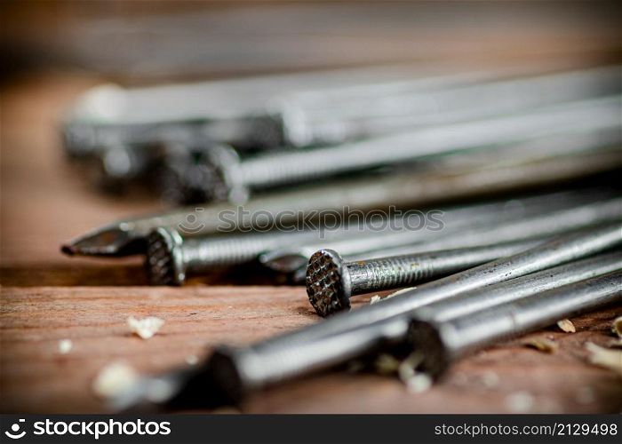 A bunch of nails on the table. On a wooden background. High quality photo. A bunch of nails on the table.