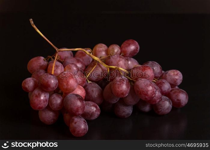 A bunch of red grapes over a black background