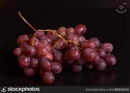 A bunch of red grapes over a black background