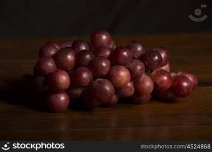 A bunch of red grapes over wooden background