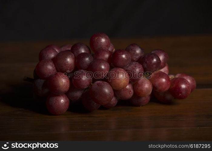 A bunch of red grapes over wooden background