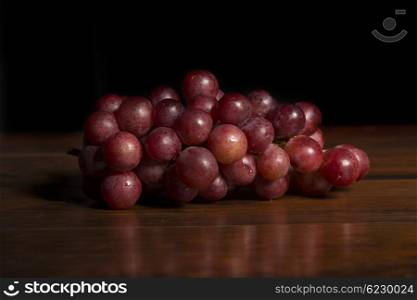 A bunch of red grapes over wooden background