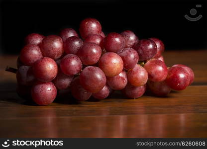 A bunch of red grapes over wooden background