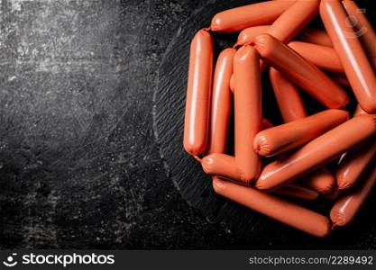 A bunch of sausages boiled on a stone board. On a black background. High quality photo. A bunch of sausages boiled on a stone board.