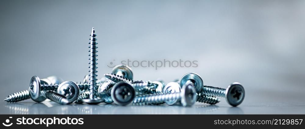 A bunch of self-tapping screws on the table. On a gray background. High quality photo. A bunch of self-tapping screws on the table.