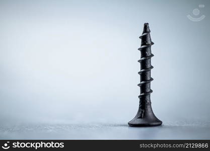 A bunch of self-tapping screws on the table. On a gray background. High quality photo. A bunch of self-tapping screws on the table.