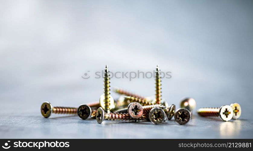 A bunch of self-tapping screws on the table. On a gray background. High quality photo. A bunch of self-tapping screws on the table.