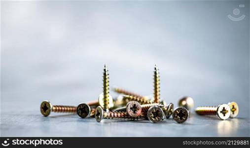 A bunch of self-tapping screws on the table. On a gray background. High quality photo. A bunch of self-tapping screws on the table.