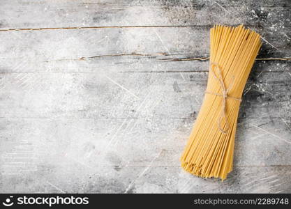 A bunch of spaghetti dry tied with a rope. On a gray background. High quality photo. A bunch of spaghetti dry tied with a rope.