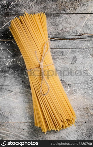 A bunch of spaghetti dry tied with a rope. On a gray background. High quality photo. A bunch of spaghetti dry tied with a rope.