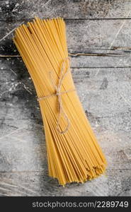 A bunch of spaghetti dry tied with a rope. On a gray background. High quality photo. A bunch of spaghetti dry tied with a rope.