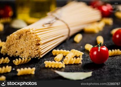 A bunch of spaghetti dry with cherry tomatoes. On a black background. High quality photo. A bunch of spaghetti dry with cherry tomatoes.