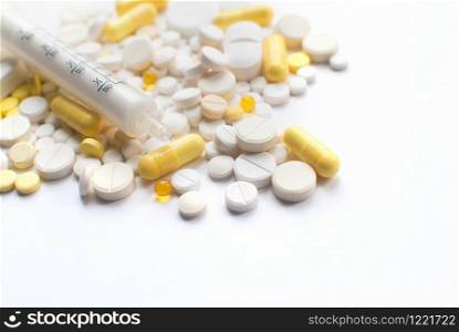 A bunch of yellow and white tablets, pills isolated on a white background with syringe. close up. Selective focus. Health day. Medical pharmacy concept. Copyspace. A bunch of yellow and white tablets, pills isolated on a white background with syringe. close up. Selective focus. Health day. Copyspace