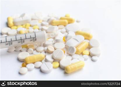 A bunch of yellow and white tablets, pills isolated on a white background with syringe. close up. Selective focus. Health day. Medical pharmacy concept. Copyspace. A bunch of yellow and white tablets, pills with syringe.