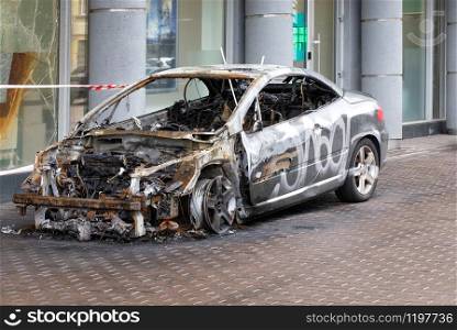 A burned-out car stands on the sidewalk of a city street, side view of a burned-out passenger compartment, image with copy space.. The interior of a burned-out car interior, side view.