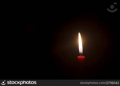 a burning candle in darkness, with copy space.