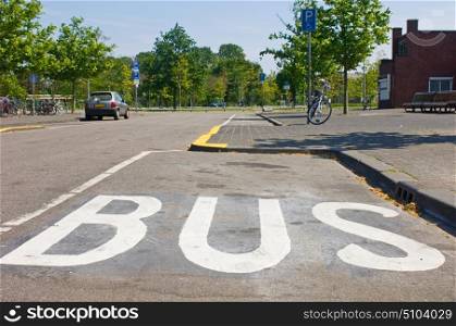 A bus stop with the marking BUS on the road in white letters