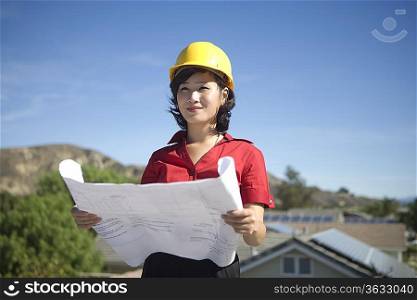 A business lady on a rooftop with plans in her hand