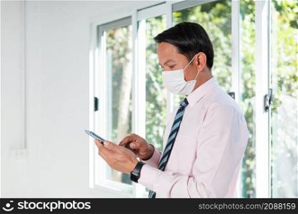 a business man standing by the window using a mobile phone