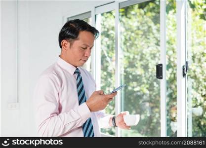 a business man standing by the window using a mobile phone