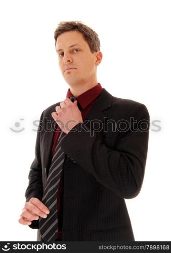 A business man standing in a suit and fixing his tie, looking serious,isolated for white background.